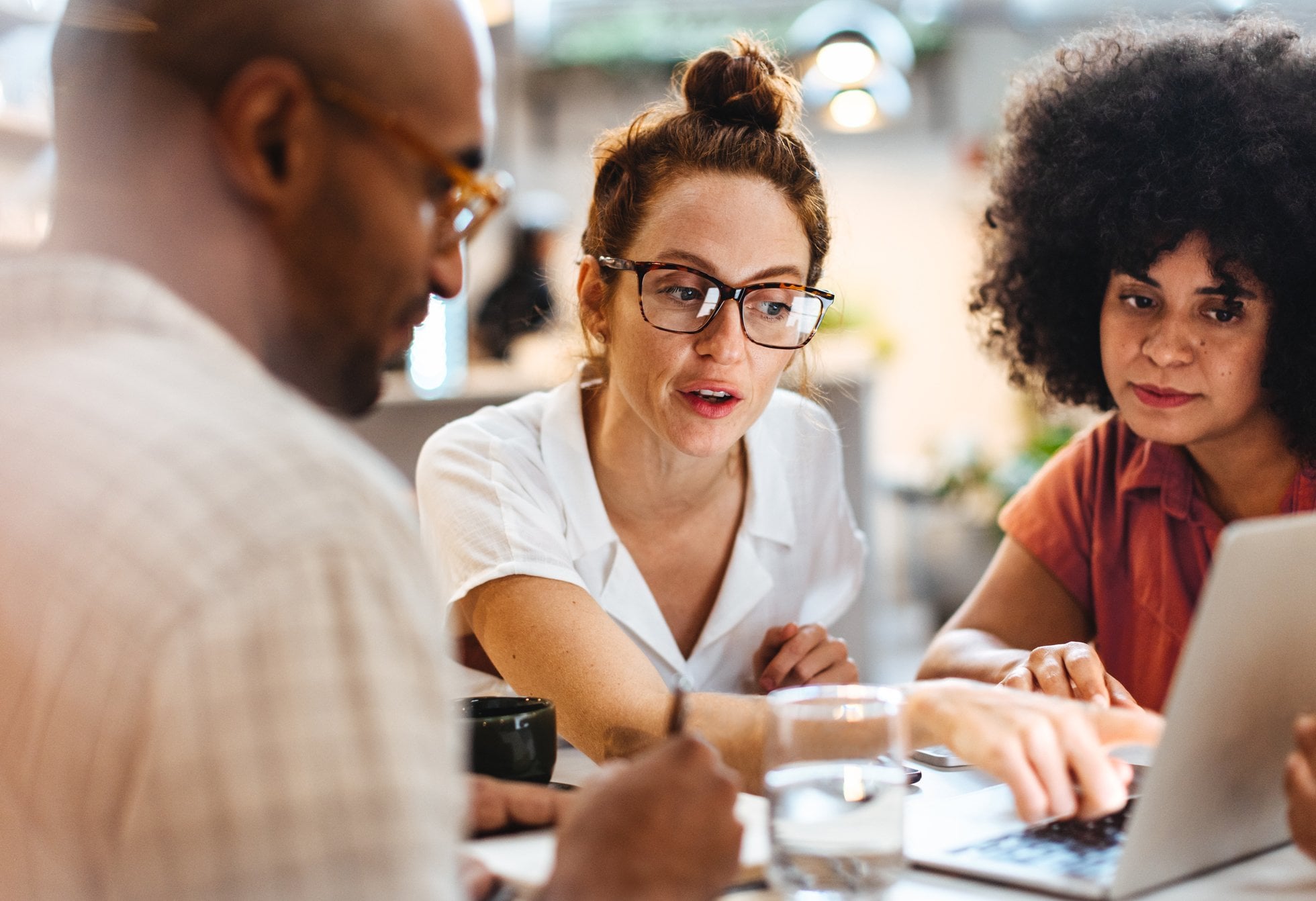 Three diverse individuals gather for a productive in-person meeting in a private meeting space.