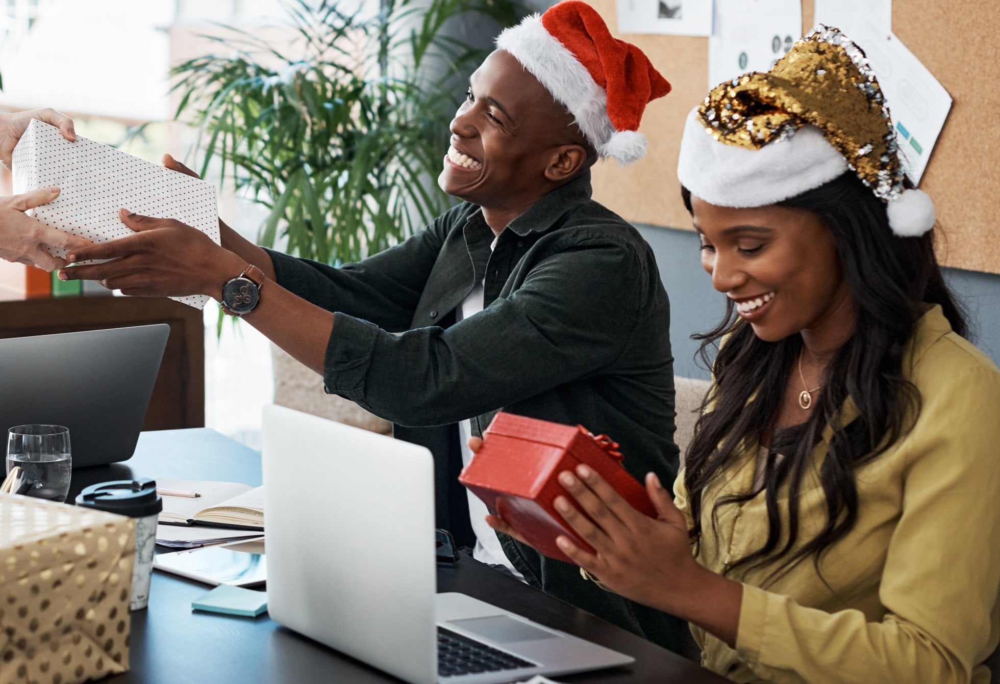 Two African-American coworkers smile and receive gifts during the holiday season in an office setting