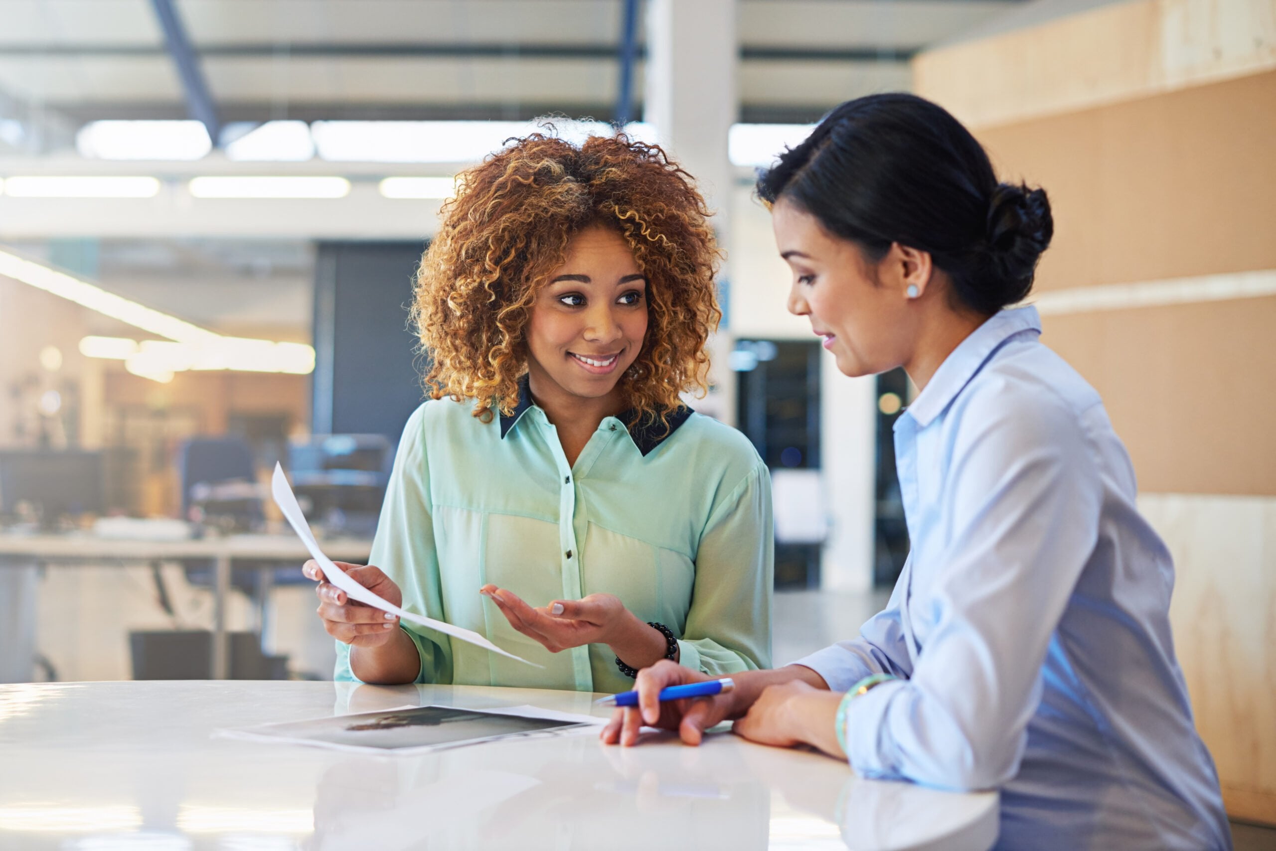 Two women talking in an office space.
